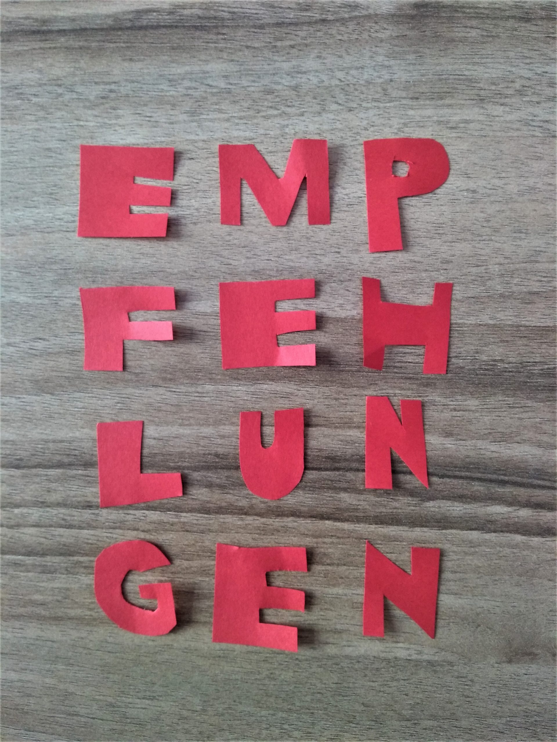 Empfehlungen - Ausgeschnittene Buchstaben auf Tisch